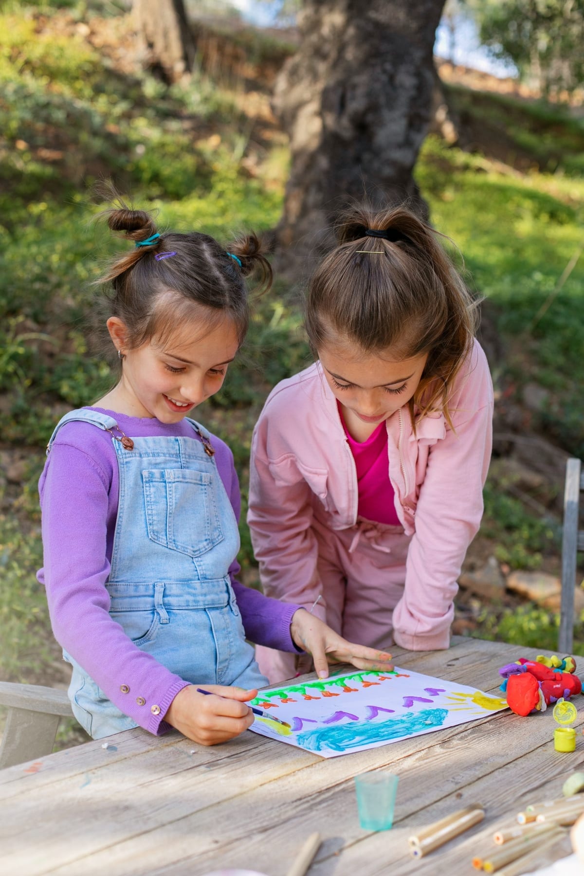 Dos niñas crean y pintan juntas al aire libre
